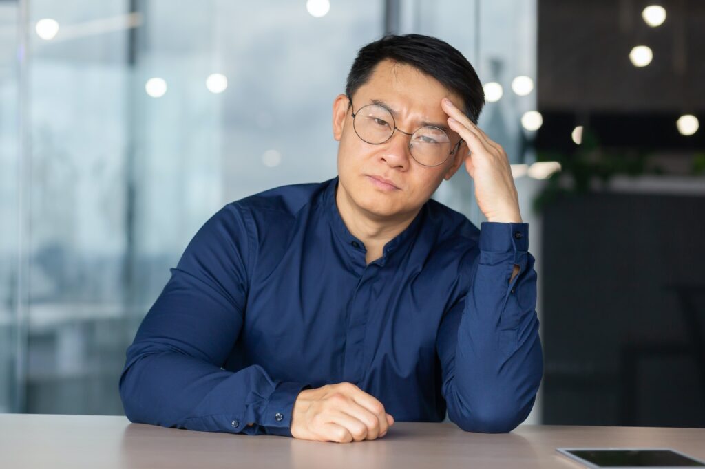 Portrait of overworked and tired office worker at workplace, asian man in glasses and shirt looking