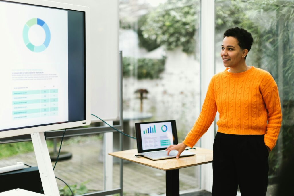 brazilian lady showing chart giving training using laptop and monitor tv in indoors classroom