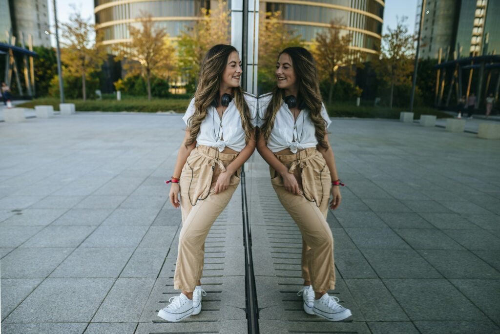 Young smiling woman reflected in glass looking at herself