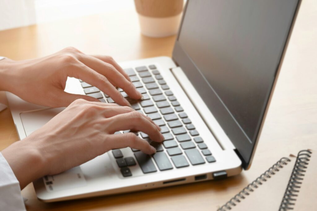 Close up hand of business woman texting on laptop.