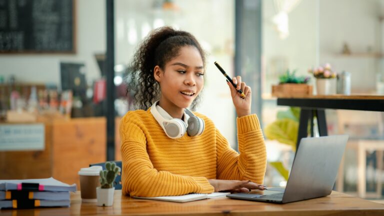 American teenage woman sitting in office with laptop, she is a student studying online with laptop a