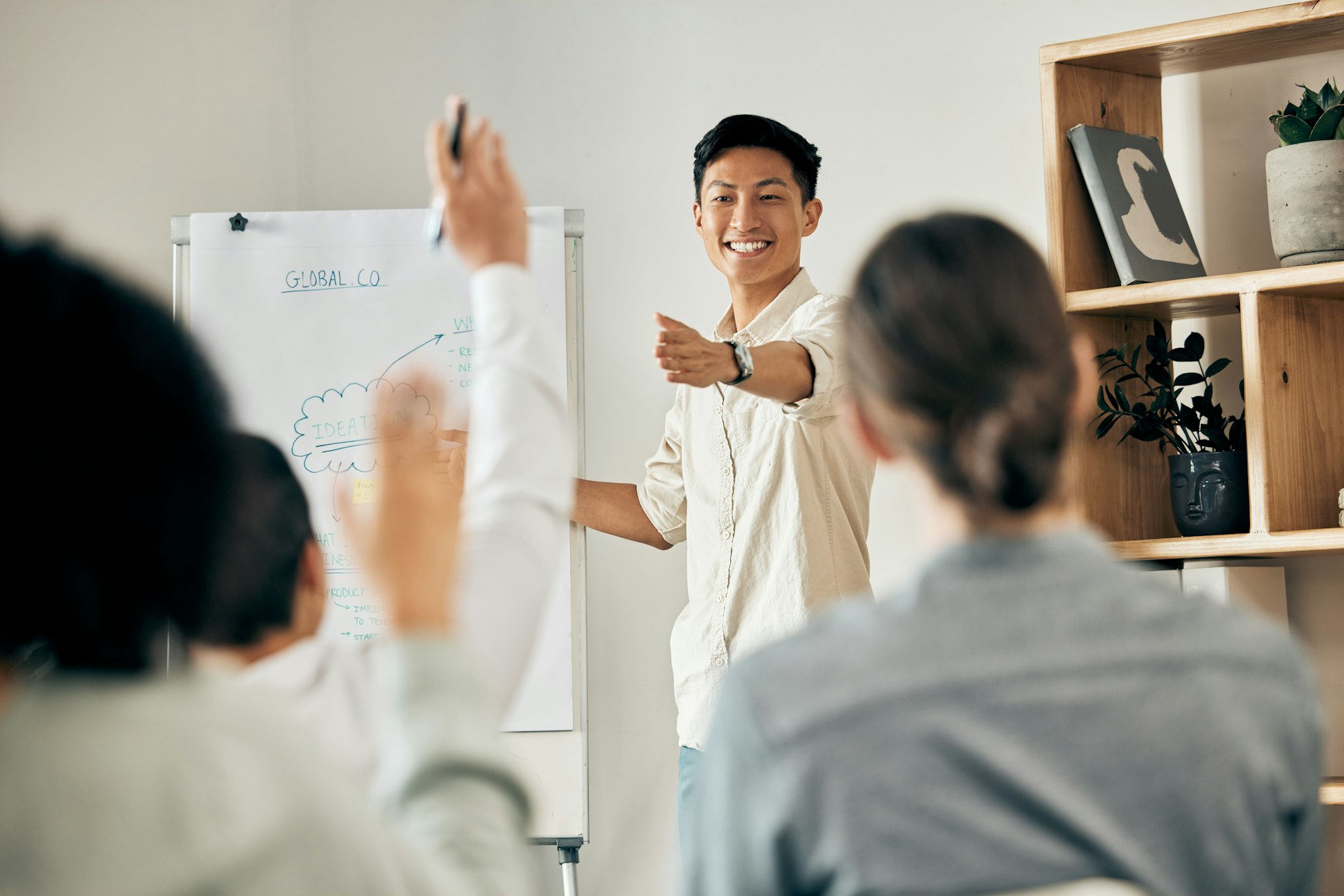 Businessman doing a presentation in a meeting with his team asking questions in a conference room.