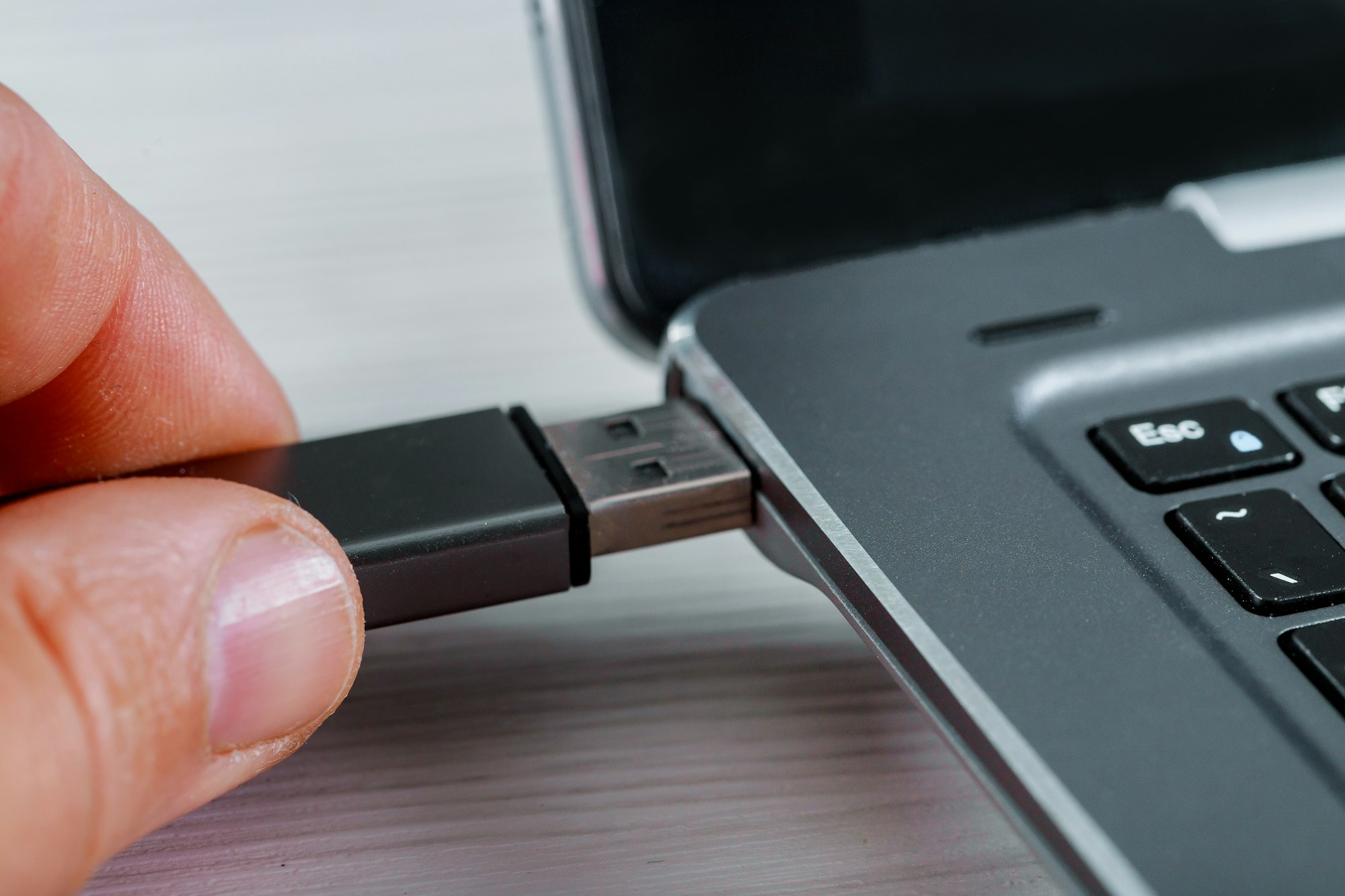 Close up of woman hand plugging inserting USB flash drive into laptop computer on white background