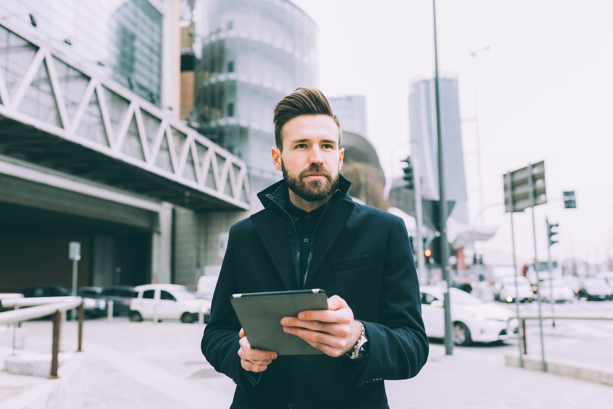 Young successful bearded business man outdoor using tablet