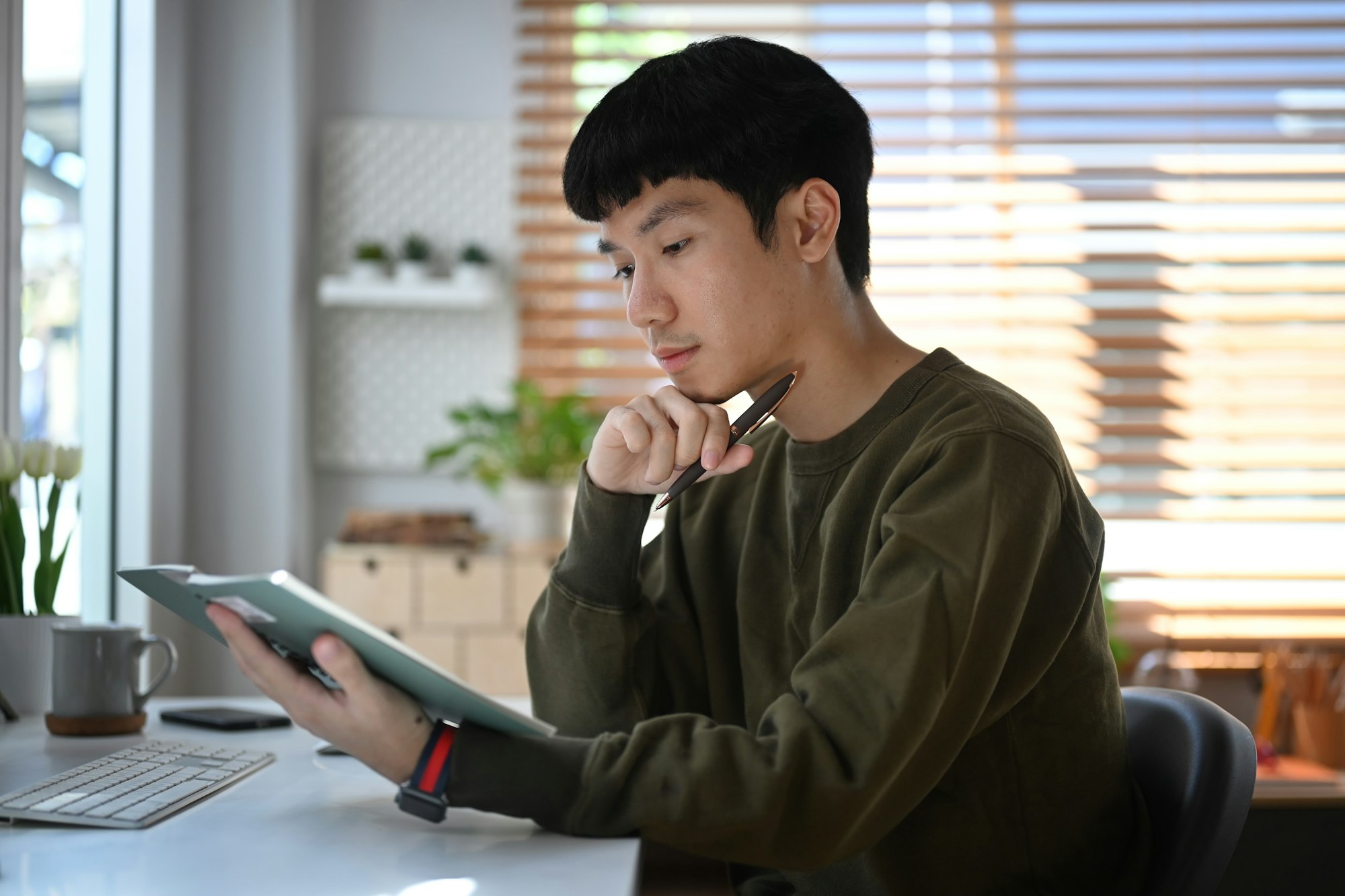 Thoughtful asian man making important notes, agenda plan planning daily appointment on notebook.