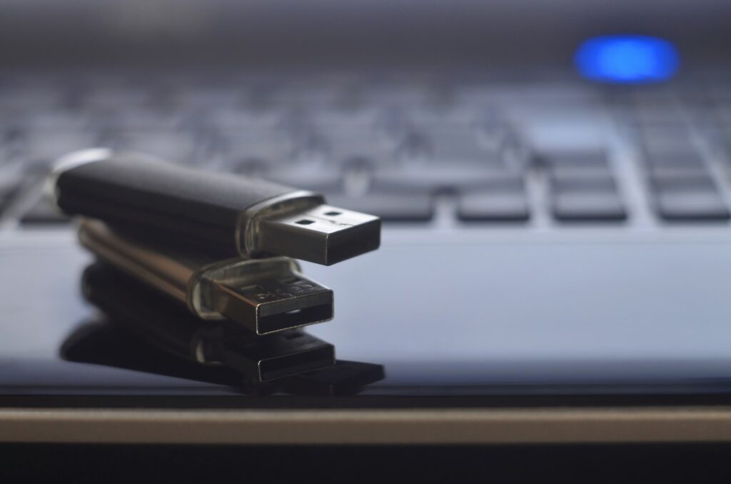 USB flash cards lying on black laptop case in front of his keyboard