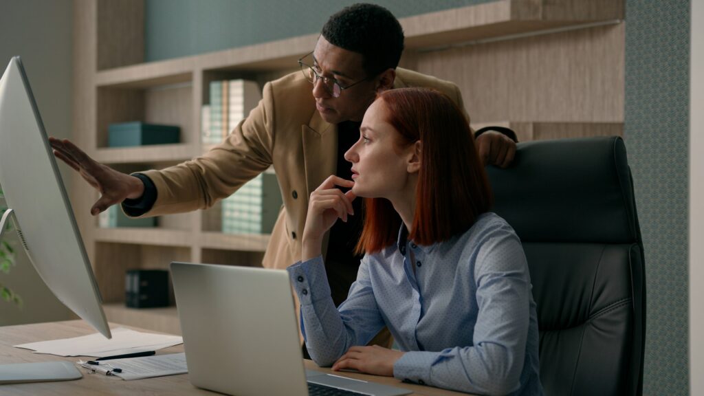 African American male mentor teaching Caucasian female employee explain online software marketing