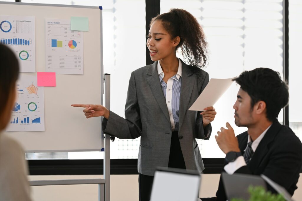 Confident female project leader giving business presentation, explaining marketing data.