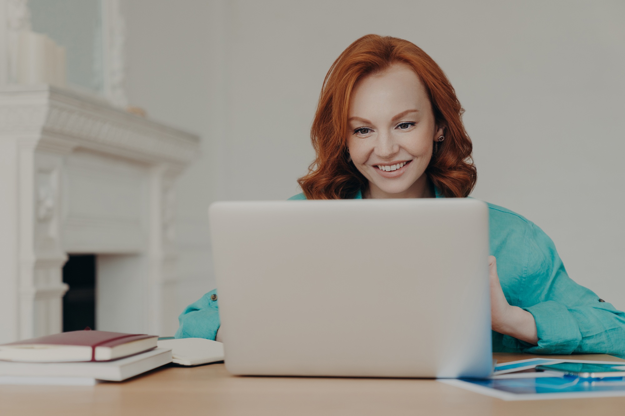 Focused cheerful redhead successful businesswoman does research, makes business project