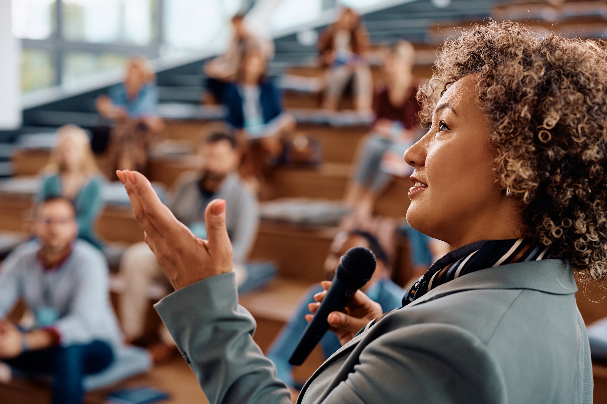 Mid adult businesswoman giving a speech to group of people during a seminar in conference hall.