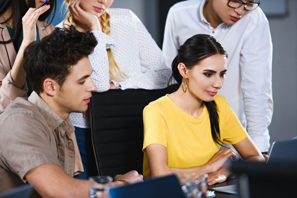 multicultural group of business colleagues watching presentation on laptop at modern office