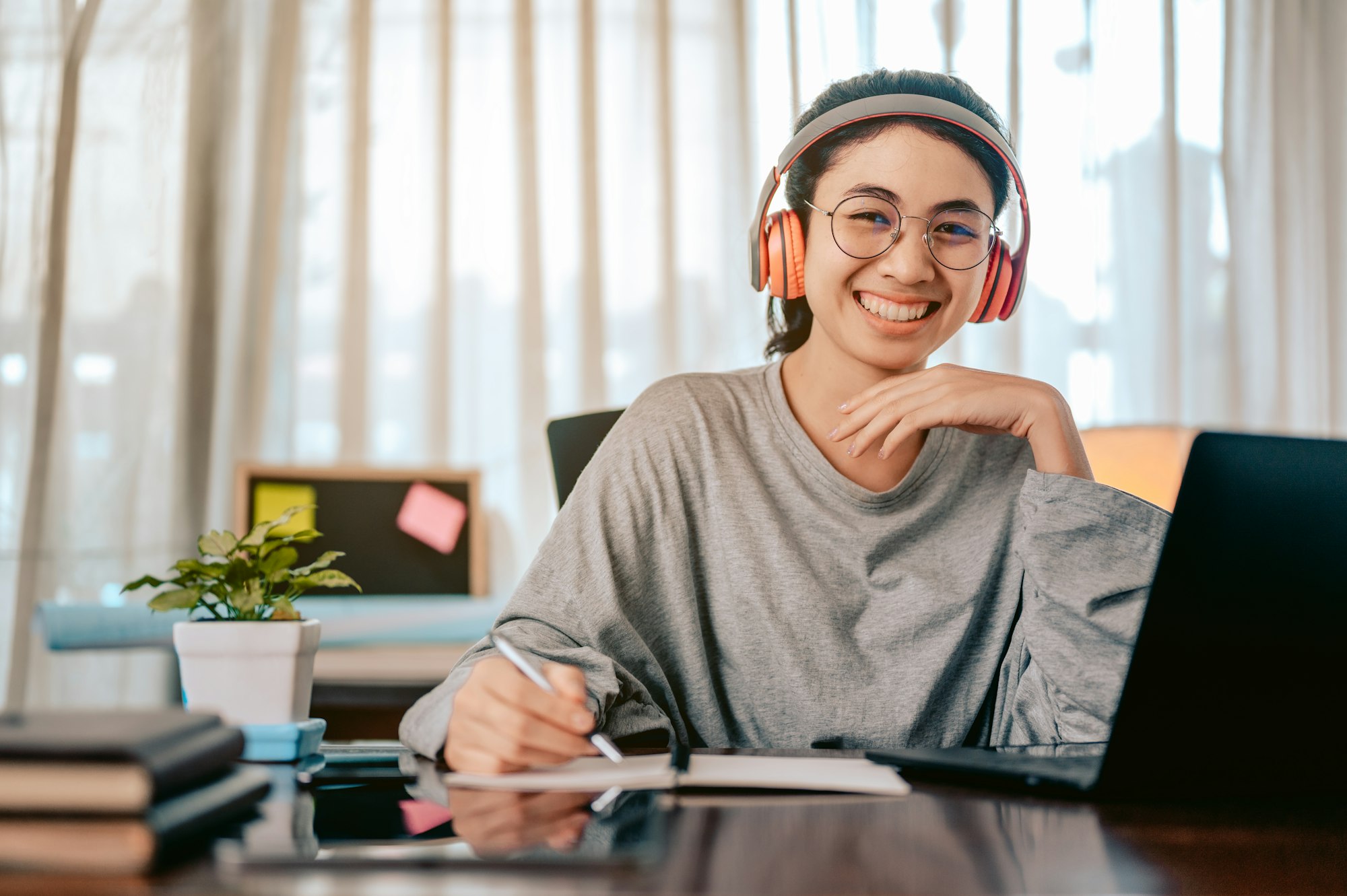 Portrait woman is working in the living room at home, wearing headphones listening to music working.