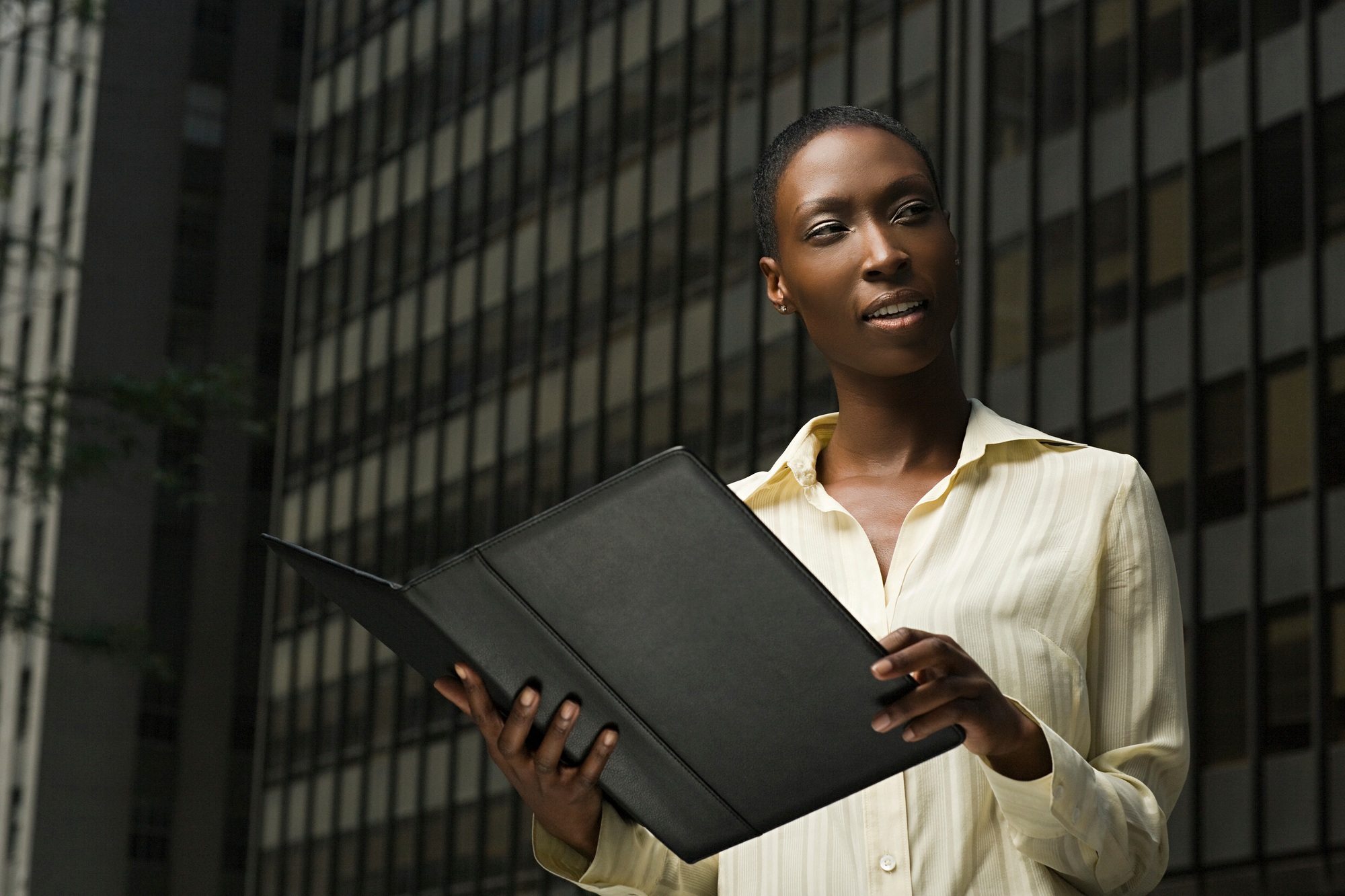 Confident professional woman with portfolio against urban backdrop